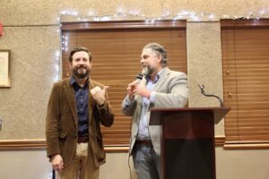 State Representatives Jared Deck and Jacob Rosecrants laughing while standing at a speaker's podium