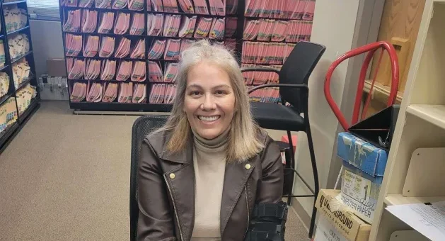A woman, Teressa, sitting in the records office of a courthouse, where she works